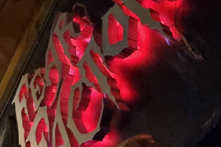 Upside-down neon sign with red glow and skull decoration on the wall.