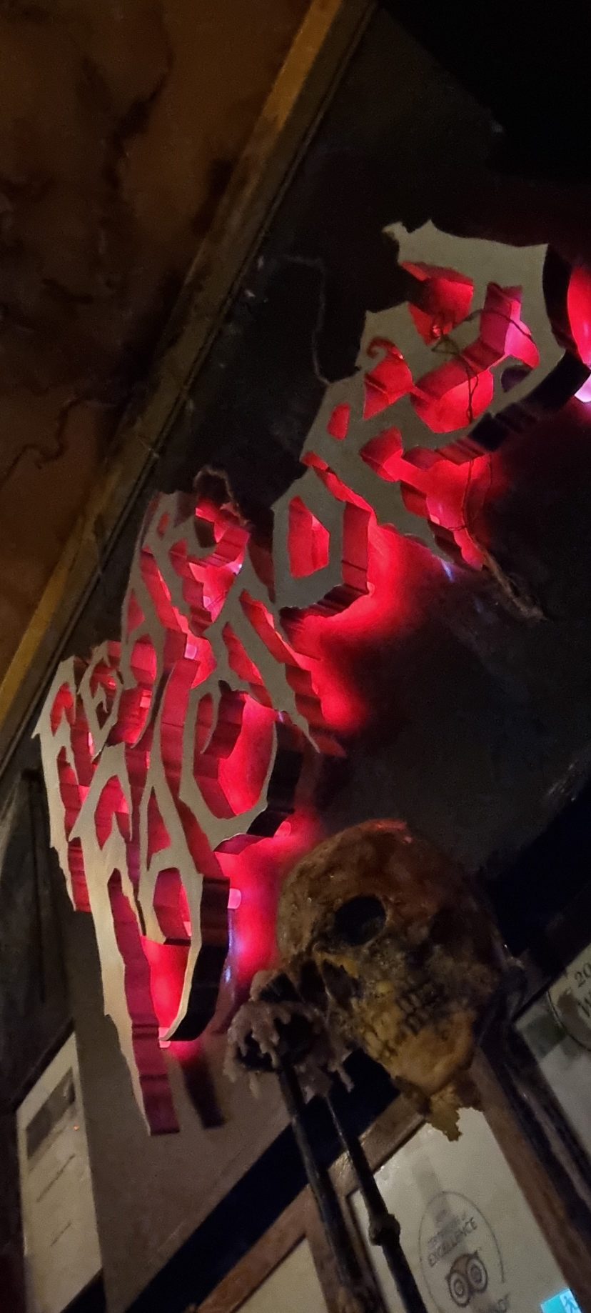 Red neon sign with abstract design and skull decoration.