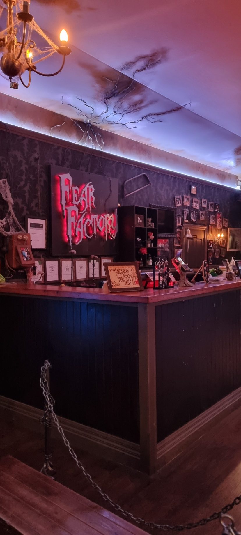 Dimly lit bar with neon 'Fear Factory' sign and various decorations.