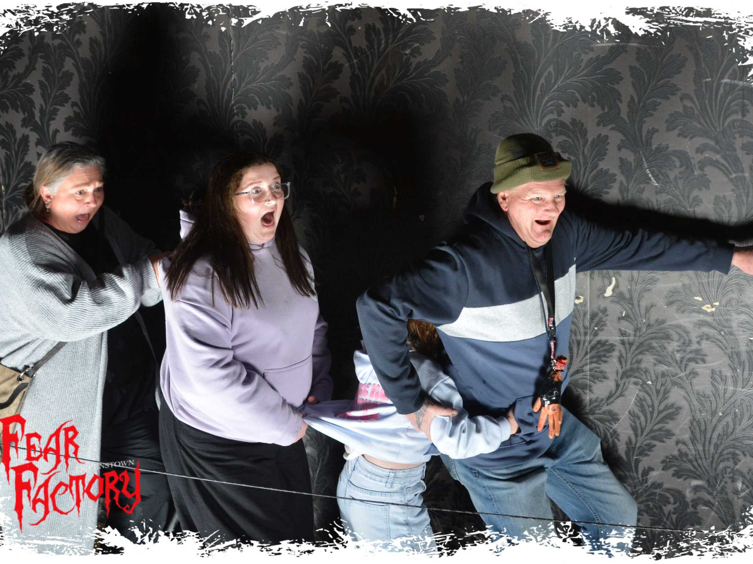 Four people in a haunted house exhibit, looking startled and scared.