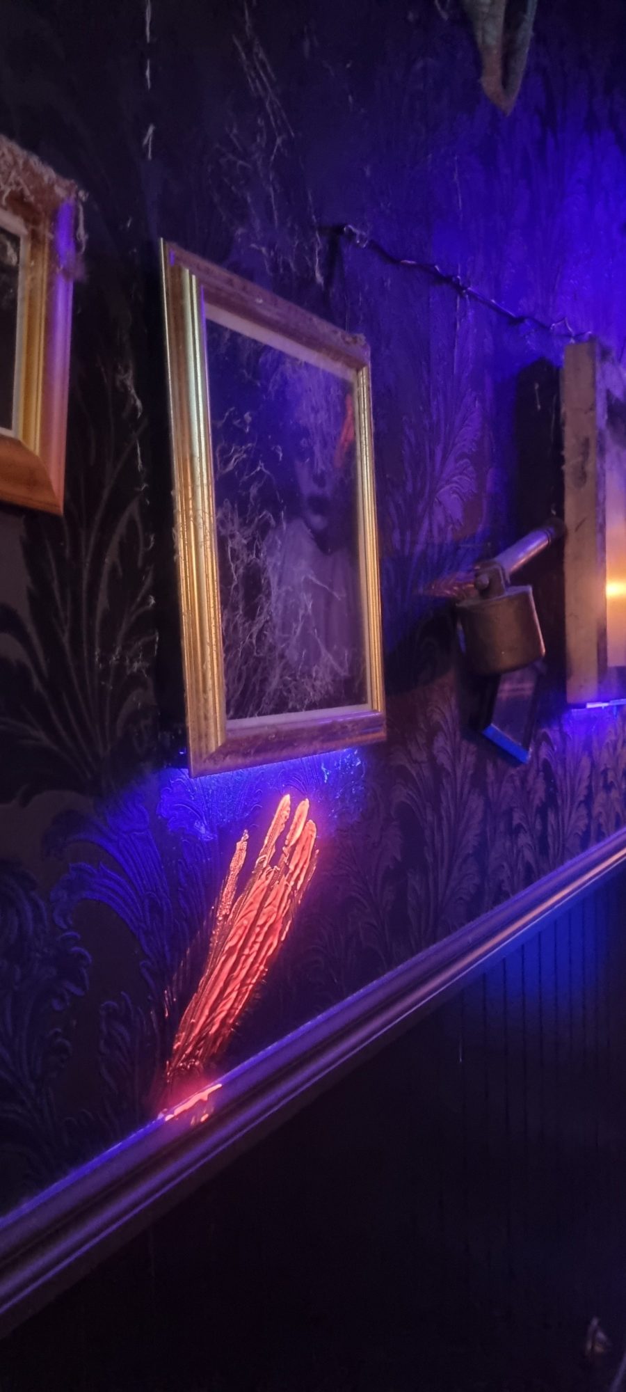 Art frames and objects on a patterned floor with blue and pink light.