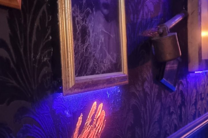 Art frames and objects on a patterned floor with blue and pink light.