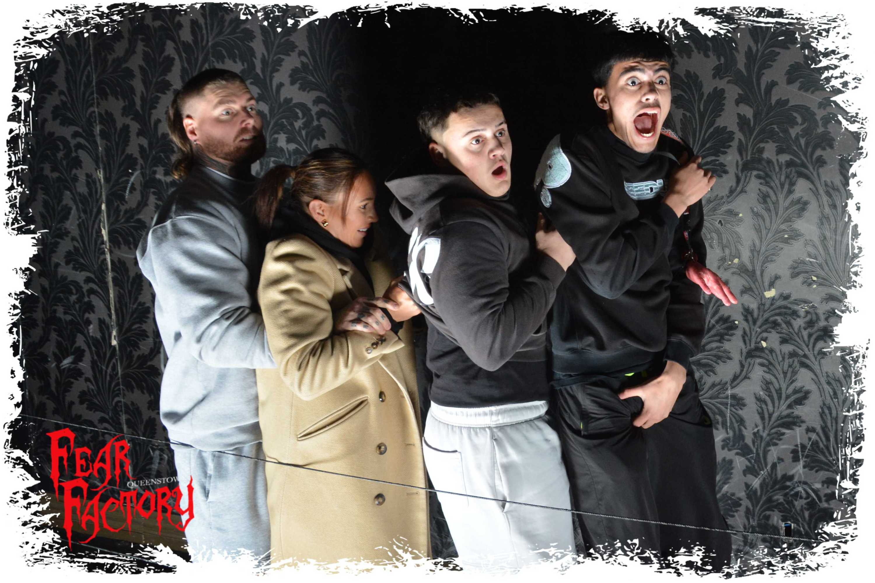 Four people in a haunted house exhibit, looking frightened.